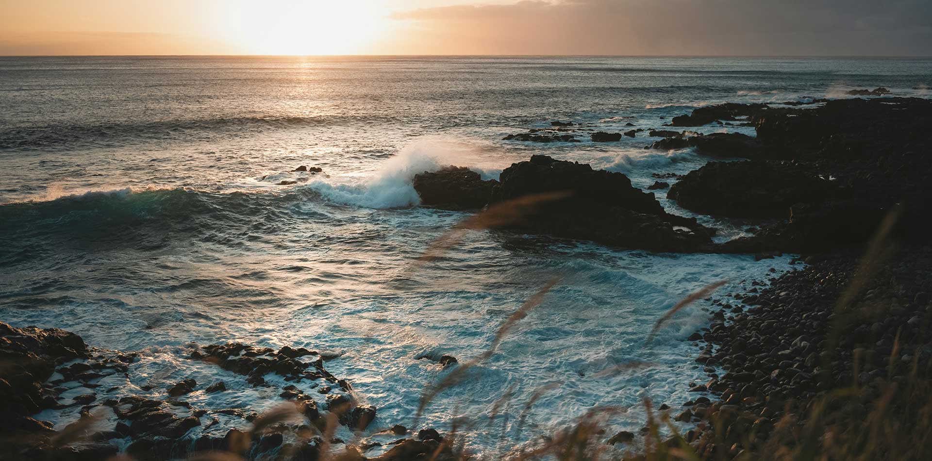 Header background: ocean waves hitting rocks at sunset